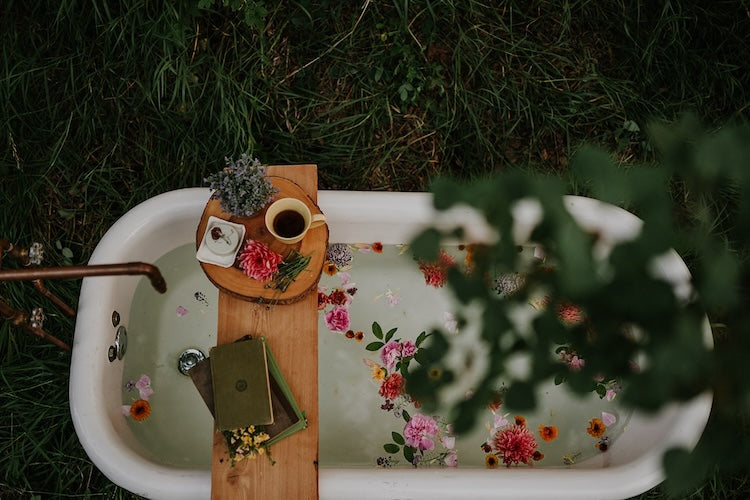 bath tub outside with flowers and books