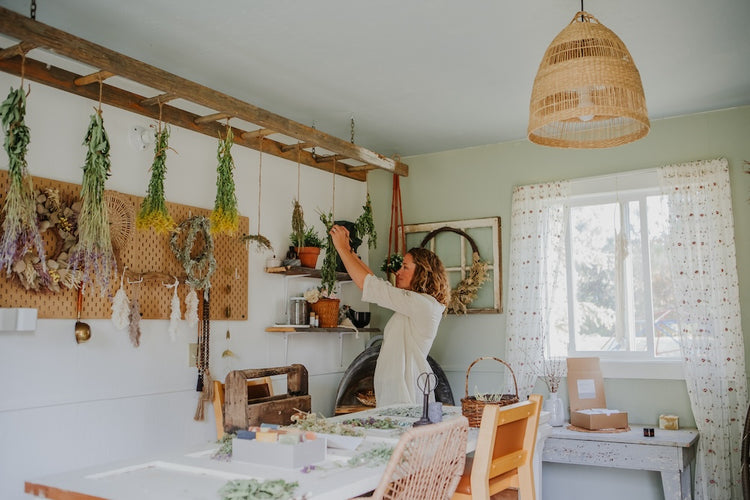 woman hanging herbs to dry from ladder